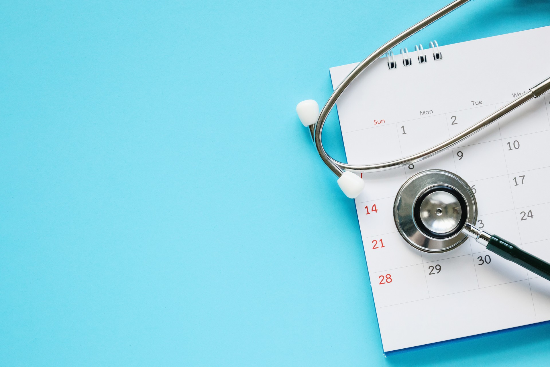 Stethoscope with calendar page date on blue background doctor appointment medical concept