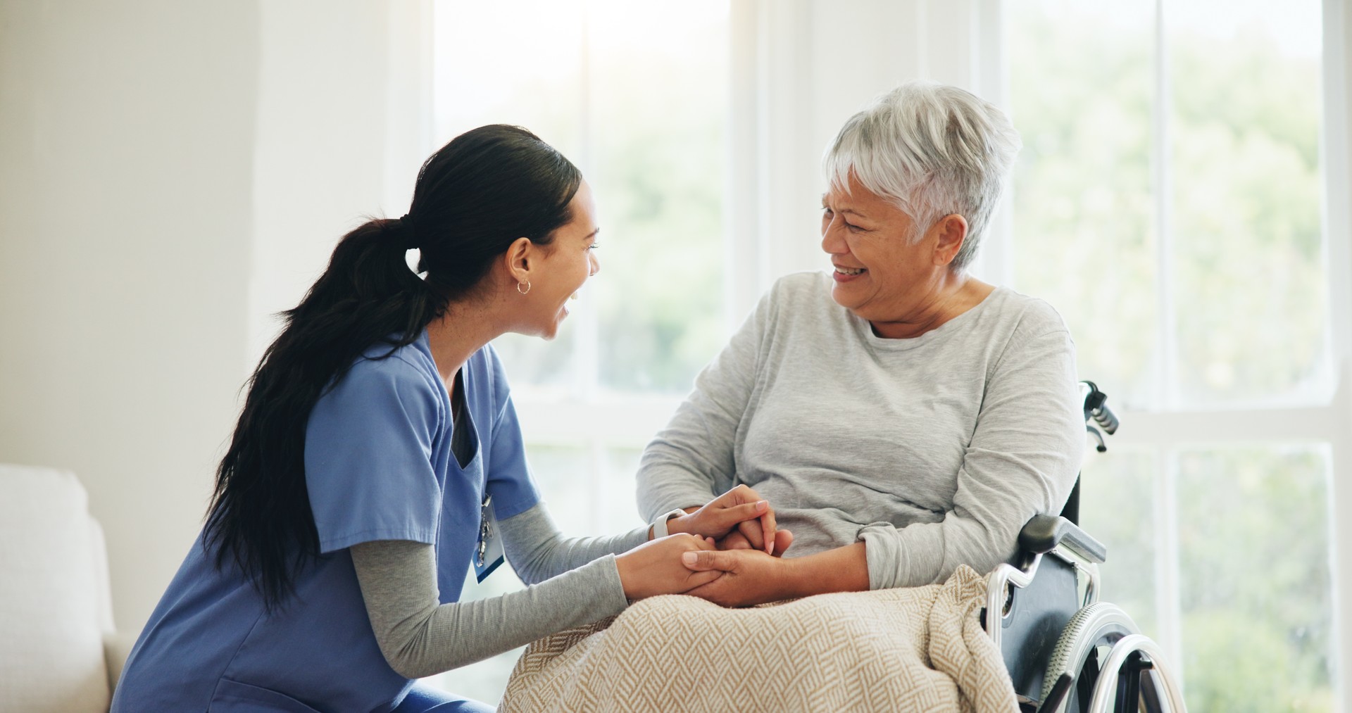 Happy woman, doctor and holding hands with senior patient in wheelchair, support or trust for healthcare at home. Medical nurse, caregiver or person with a disability smile for care or help at house